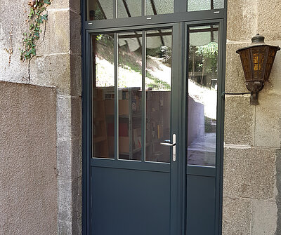 porte alu grise sur mur en pierre